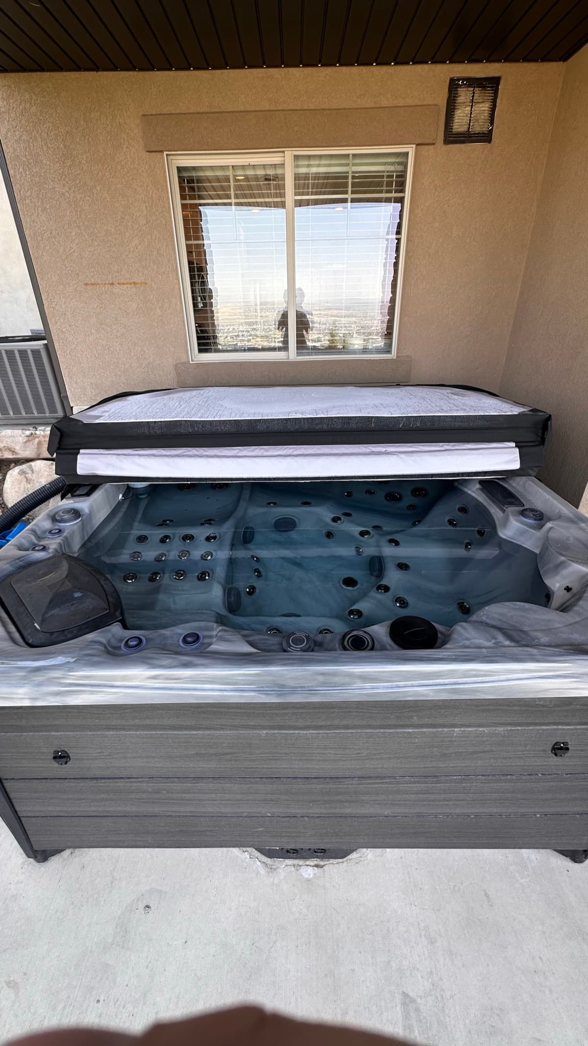Modern gray hot tub on patio with cover open